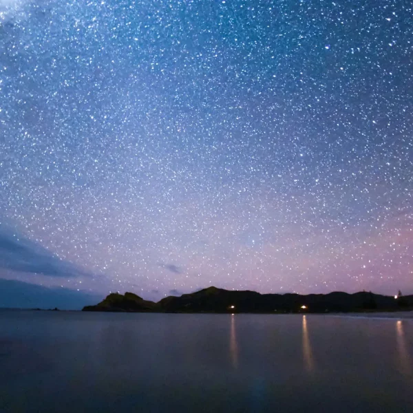 Medlands Beach glimmers in the moonlight, a testament to Aotea/Great Barrier Island's commitment to preserving the dark, star-filled skies. Photo / Mark Russell