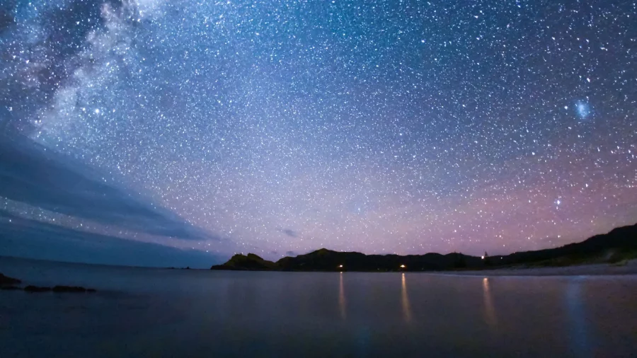 Medlands Beach glimmers in the moonlight, a testament to Aotea/Great Barrier Island's commitment to preserving the dark, star-filled skies. Photo / Mark Russell