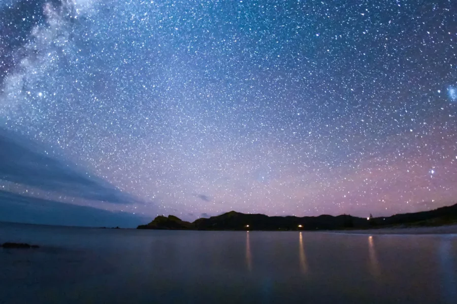 Medlands Beach glimmers in the moonlight, a testament to Aotea/Great Barrier Island's commitment to preserving the dark, star-filled skies. Photo / Mark Russell