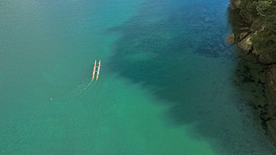 An aerial view captures the Waka ama 'Hukatai' as it is paddled across the serene waters of Aotea. Photo / Hillary Outdoors