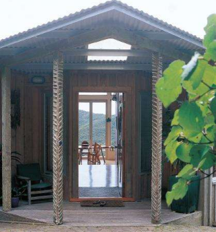 Nikau leaves have been braided around the posts at the front door. The scalloped roof line is visible from the garden. Each locally crafted dining chair is unique.