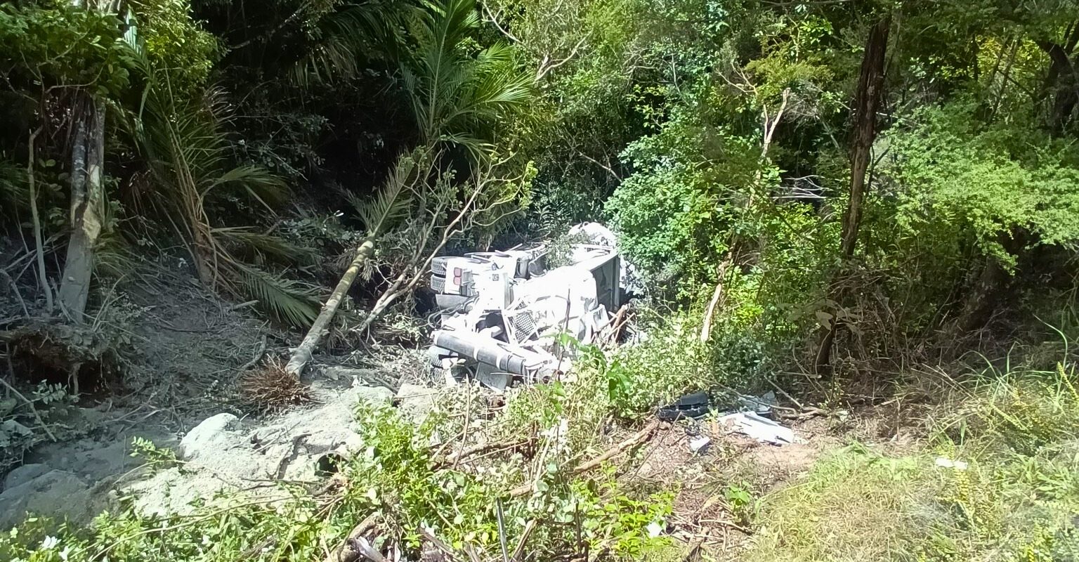 An Aotea Contractors truck lies at the bottom of a steep, bush-covered bank below Medland Road.